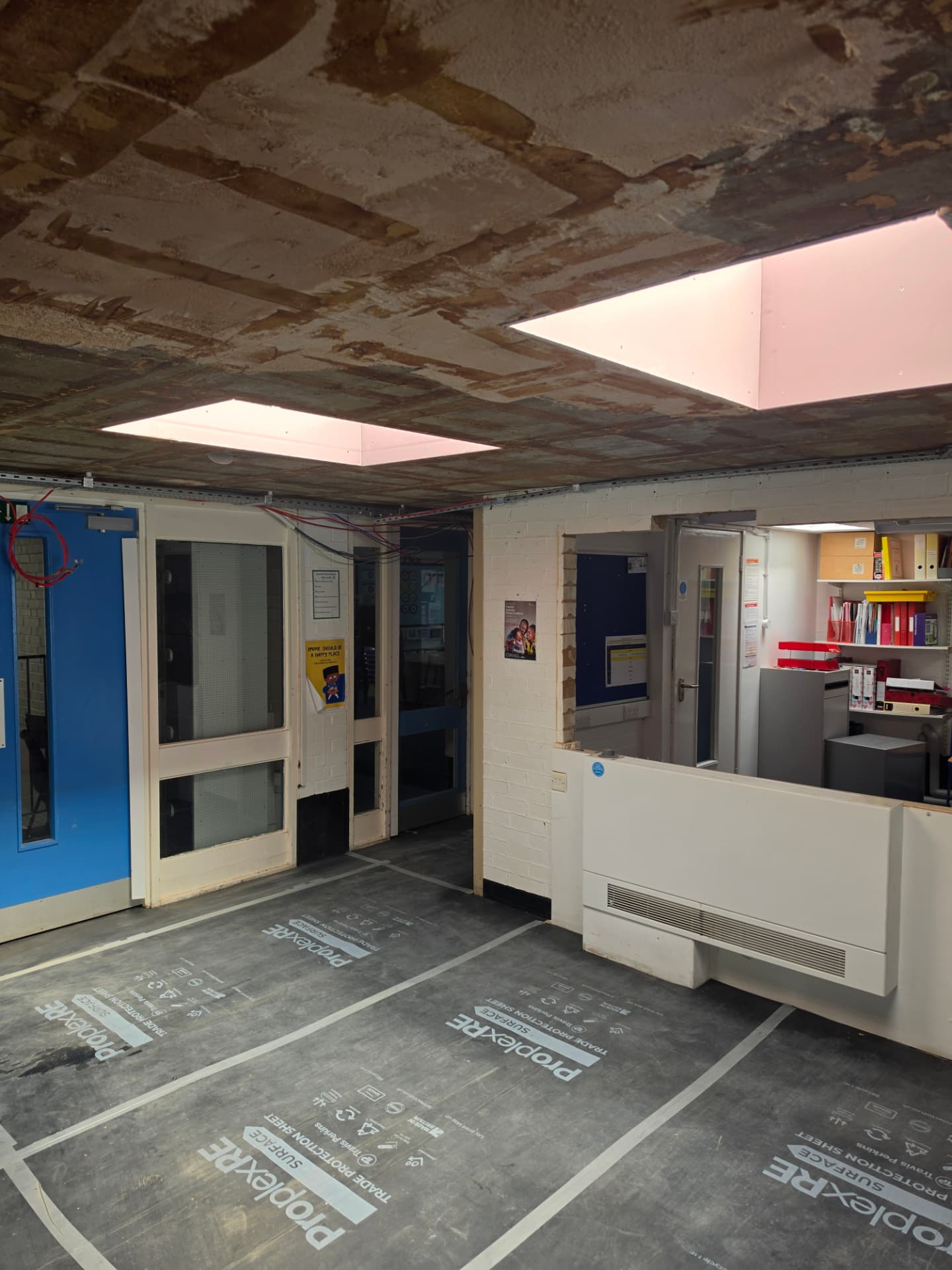 Corridor with the suspended grid ceiling removed and the void exposed.