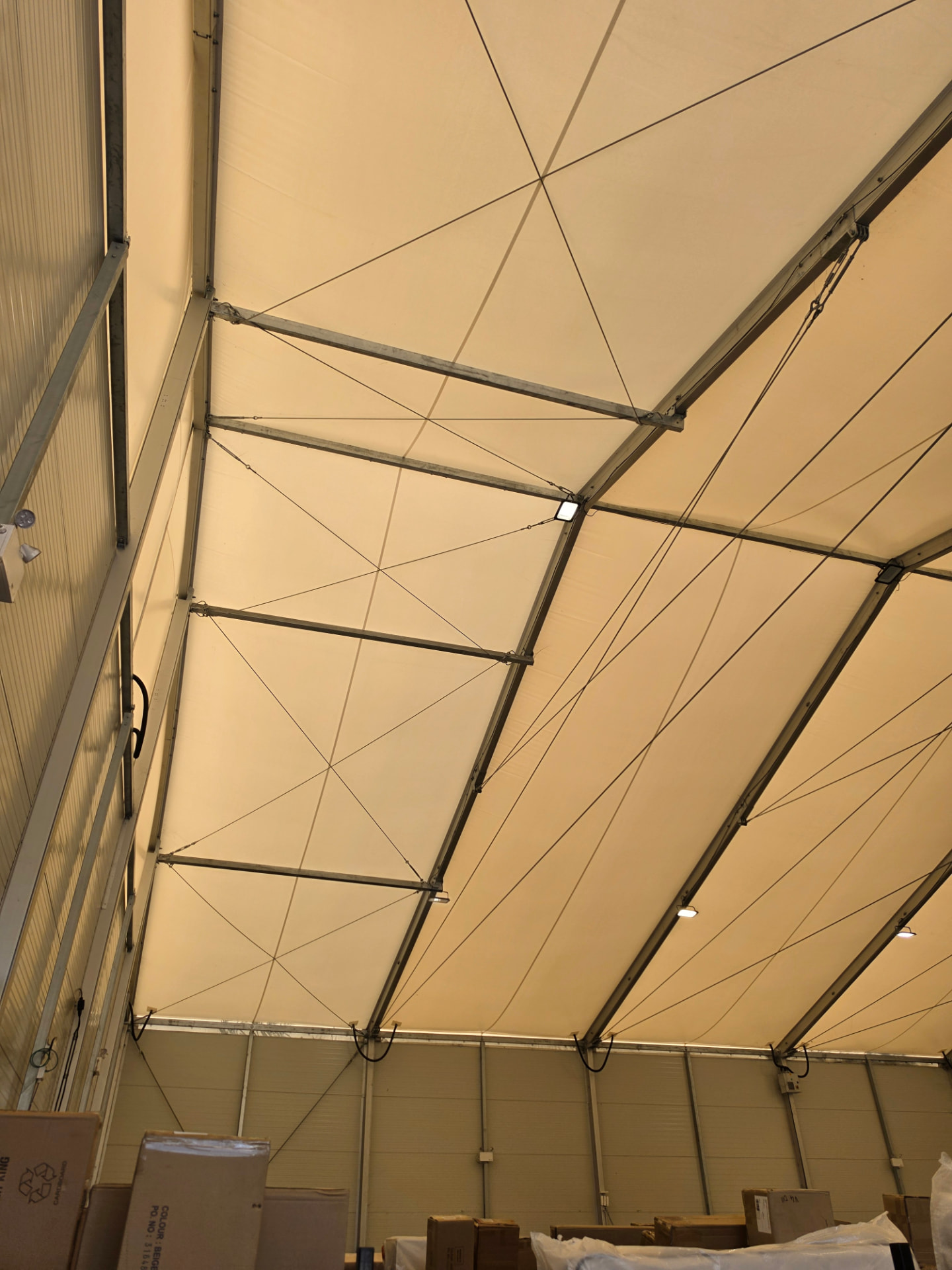 Warehouse roof structure with lighting fittings mounted along the frame.