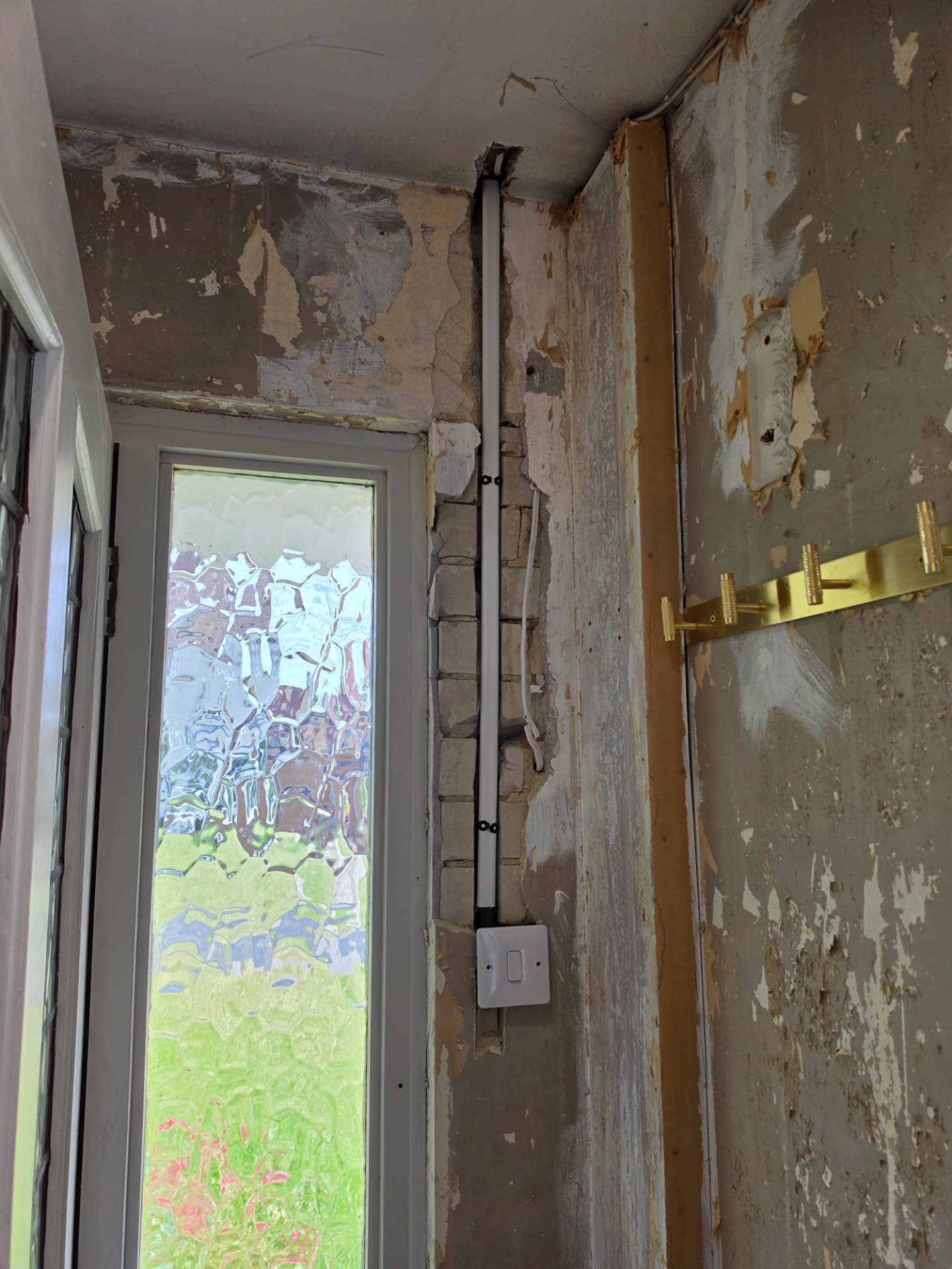 Surface conduit and a light switch fitted beside an entrance door before making good.
