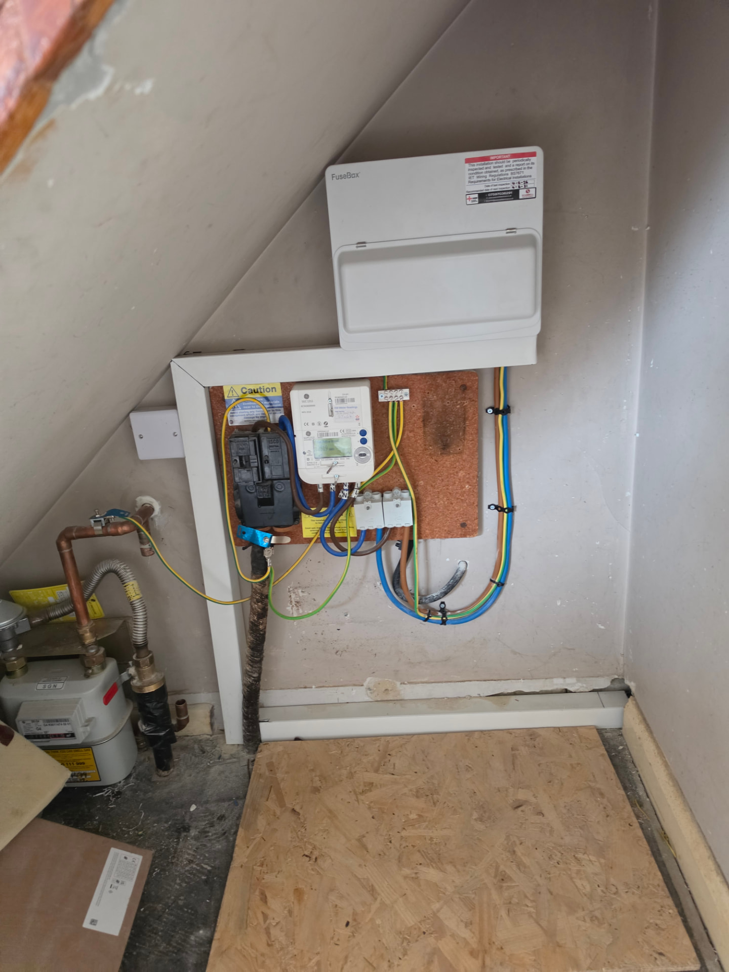 Newly installed consumer unit above the meter board in an under-stairs cupboard.